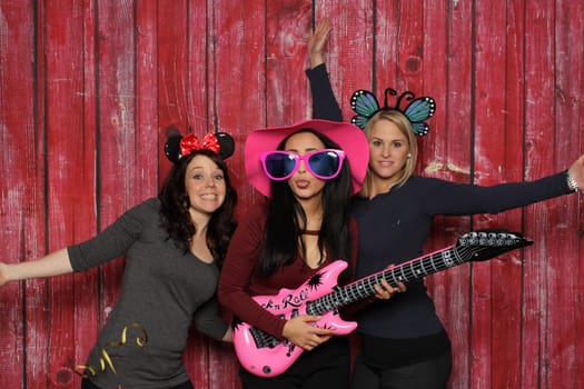Girl trio with guitars in front of a photo booth