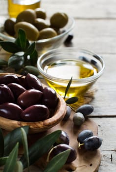 Olive oil and olives on rustic wood background