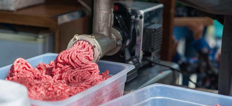 Tray of fresh minced meat. machine that puts the meat back into the machine.