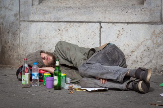Berlin, Germany - Sept 18: Homeless young alcohol addict lying drunk on street sidewalk on 18th of September ,2016 in Berlin, Germany.