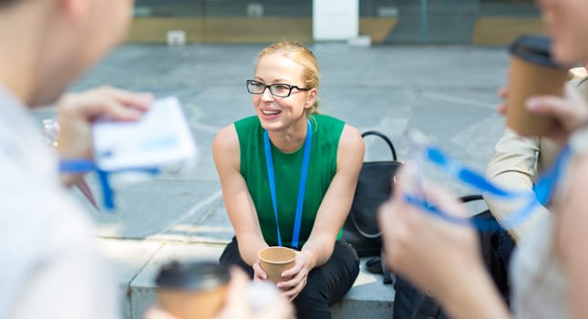Cheerful colleagues meeting on stairs outdoor for in a quick coffee break. Coffee to go.