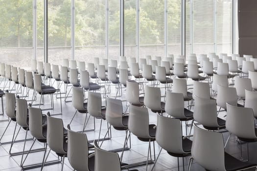 Interior of empty contemporary conference hall with white chairs.