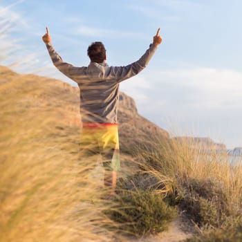 Sporty active man, arms raised, enjoying beauty of nature, freedom and life at beautiful landscape. Active lifestyle outdoors. Made it.