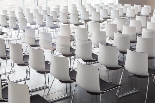 Interior of empty contemporary conference hall with white chairs.