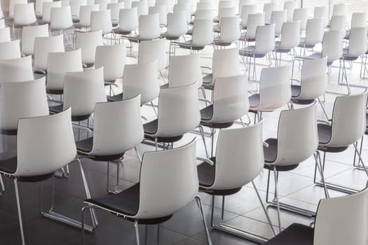 Interior of empty contemporary conference hall with white chairs.