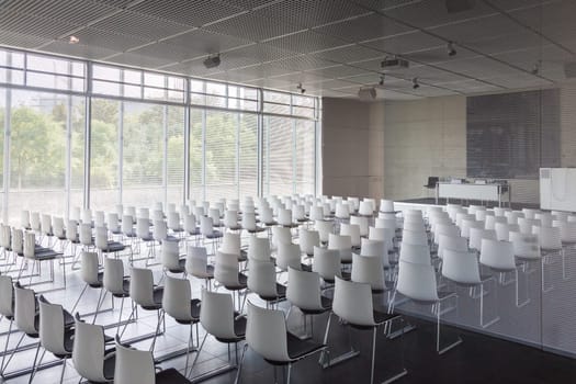 Interior of empty contemporary conference hall with white chairs.