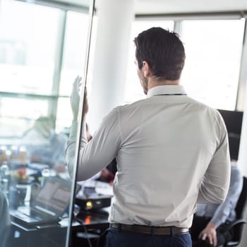 Business man making a presentation at office. Business executive delivering a presentation to his colleagues during meeting or in-house business training, explaining business plans to his employees.
