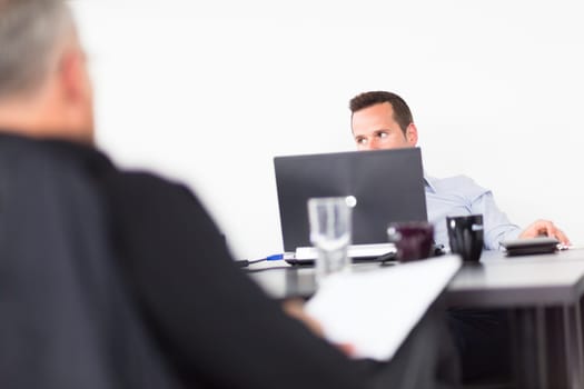 Workplace in modern office with businessman working on laptop during the meeting.