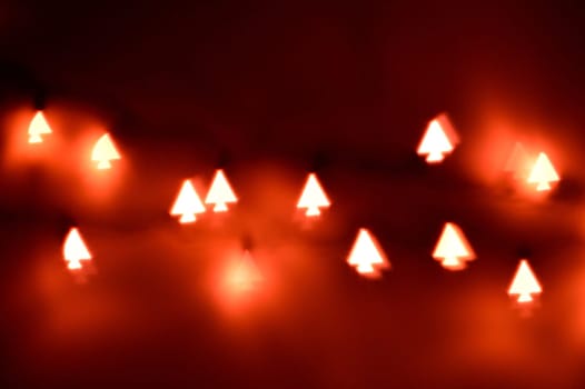 Bokeh Christmas lights in shapes of little Christmas trees. Happy Christmas time background.