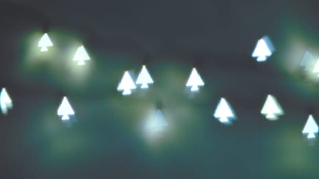 Bokeh Christmas lights in shapes of little Christmas trees. Happy Christmas time background.