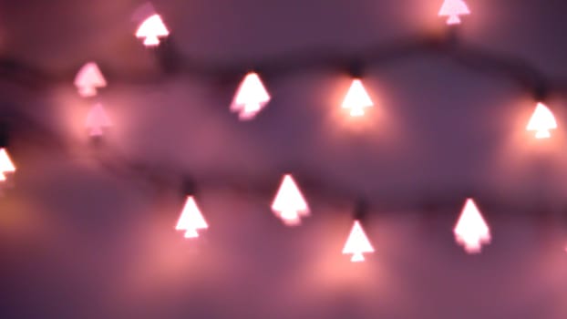 Bokeh Christmas lights in shapes of little Christmas trees. Happy Christmas time background.