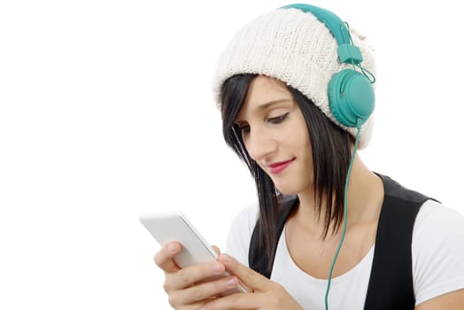young brunette listening to music with headphones and  phone on white