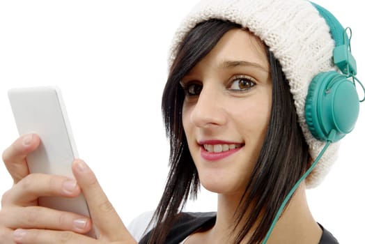 young brunette listening to music with headphones and  phone on white