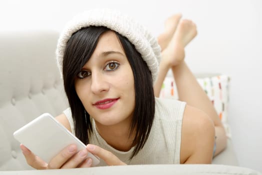 young brunette girl student lying on the couch with phone