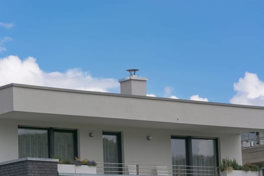Upper floor of a modern residential building in bungalow style with flat roof in front of blue sky..
