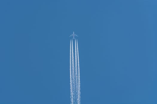 Aircraft flying at high altitude. Contrails against a dark blue sky..