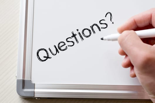 Human hand writing questions on whiteboard