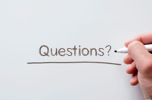 Human hand writing questions on whiteboard
