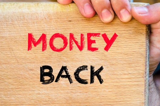 Human hand over wooden background and money back text concept