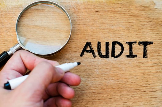Human hand over wooden background and audit text concept
