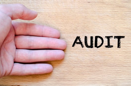 Human hand over wooden background and audit text concept