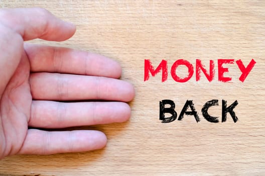 Human hand over wooden background and money back text concept