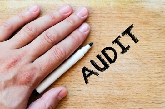 Human hand over wooden background and audit text concept
