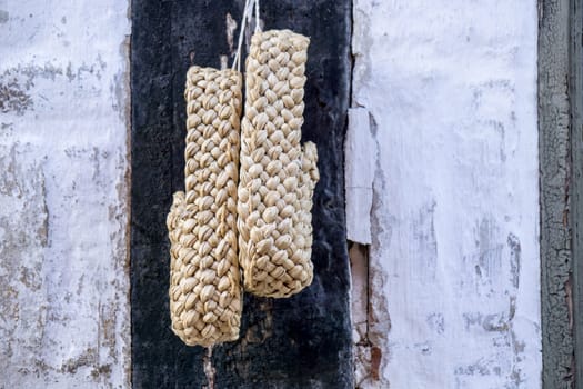 a pair of plaited straw shoes hangs on the wall