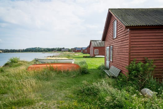 Idyllic small red Holiday cottages at a lake shore with boats lying outside