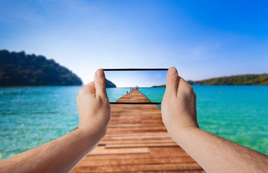 Tourism Concept. Old wooden pier. paradise island. Hand with a smartphone. Taking photo