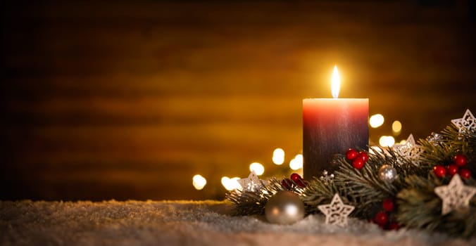 Burning candle and Christmas decoration over snow and wooden background,elegant low-key shot with festive mood