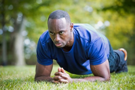 young black man wearing athletic wear doing exercise in the fall park
