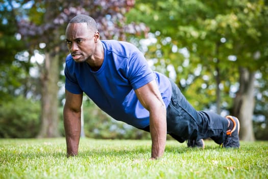 young black man wearing athletic wear doing exercise in the fall park