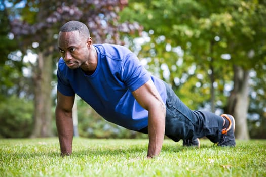 young black man wearing athletic wear doing exercise in the fall park