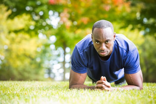 young black man wearing athletic wear doing exercise in the fall park