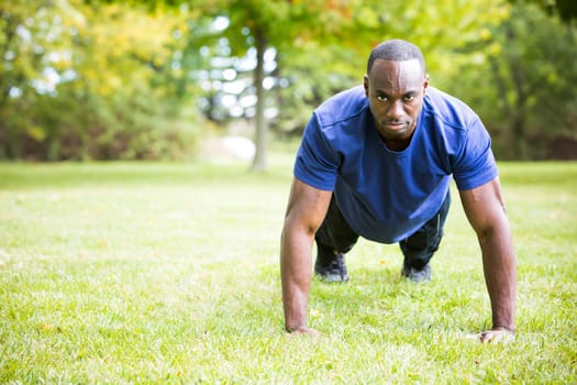 young black man wearing athletic wear doing exercise in the fall park
