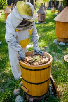 Beekeeper on apiary.  Working apiarist.  Beekeeper holding frame of honeycomb