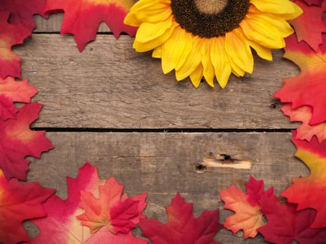 Autumn background with leaves and sunflowers on a rustic wooden plank with space for text