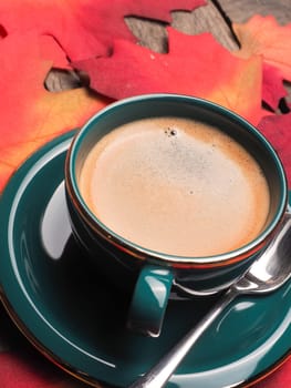 Delicious cup of espresso in a green cup, close up shot on autumn leaves decoration