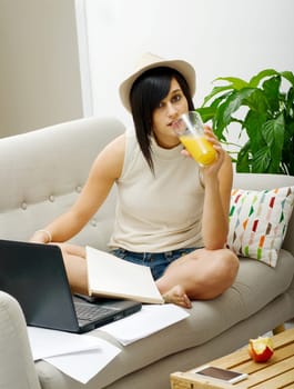 pretty young student drinking orange juice in couch at home