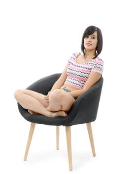 young brunette woman sitting in a armchair isolated on white background