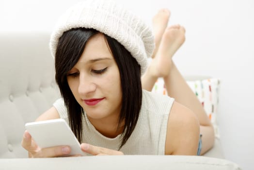 young brunette girl student lying on the couch with phone