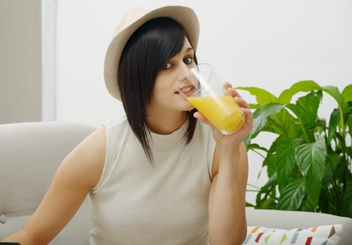 pretty young student drinking orange juice in couch at home