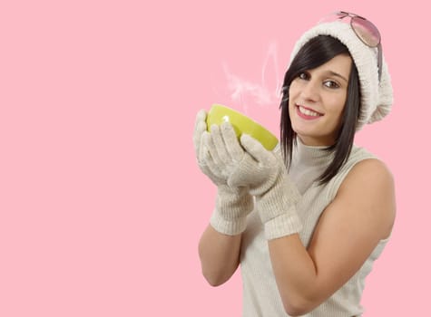 pretty young brunette woman with a cup of tea on pink background