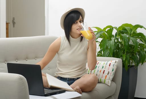 young student drinking orange juice in couch at home