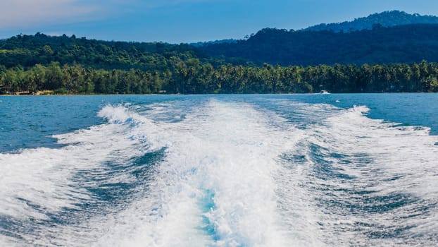 Water stream after speed boat.  Trail on water surface behind of fast moving motor boat. Waves on blue sea