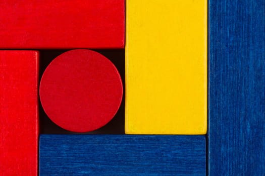 top view abstract color composition with square wood toy building blocks and a round one in the middle
