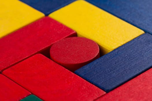 abstract color composition with square wood toy building blocks and a round one in the middle