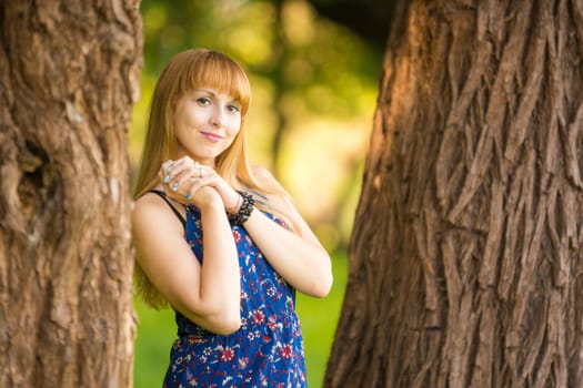 Happy young beautiful girl standing between two trees