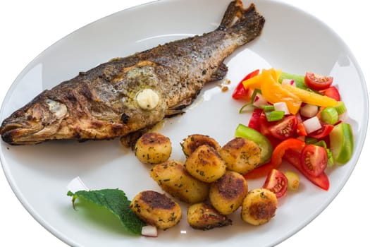 Fried trout on a white plate with lemons and fried potato..